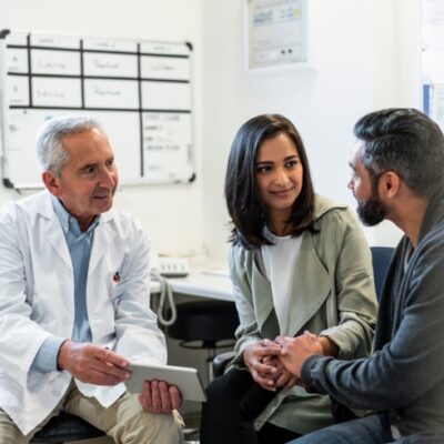 Doctor Discussing RPM Readings With Couple Over Digital Tablet