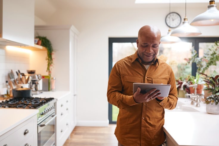 Man In Kitchen Checking Readings On Tablet