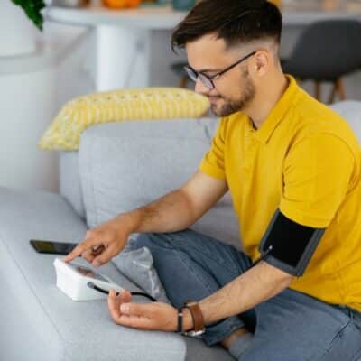 Man on couch taking blood pressure reading