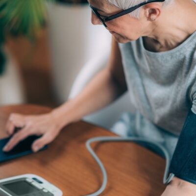 Woman taking blood pressure and checking results on phone