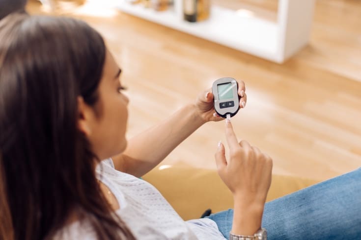 Young woman using glucometer